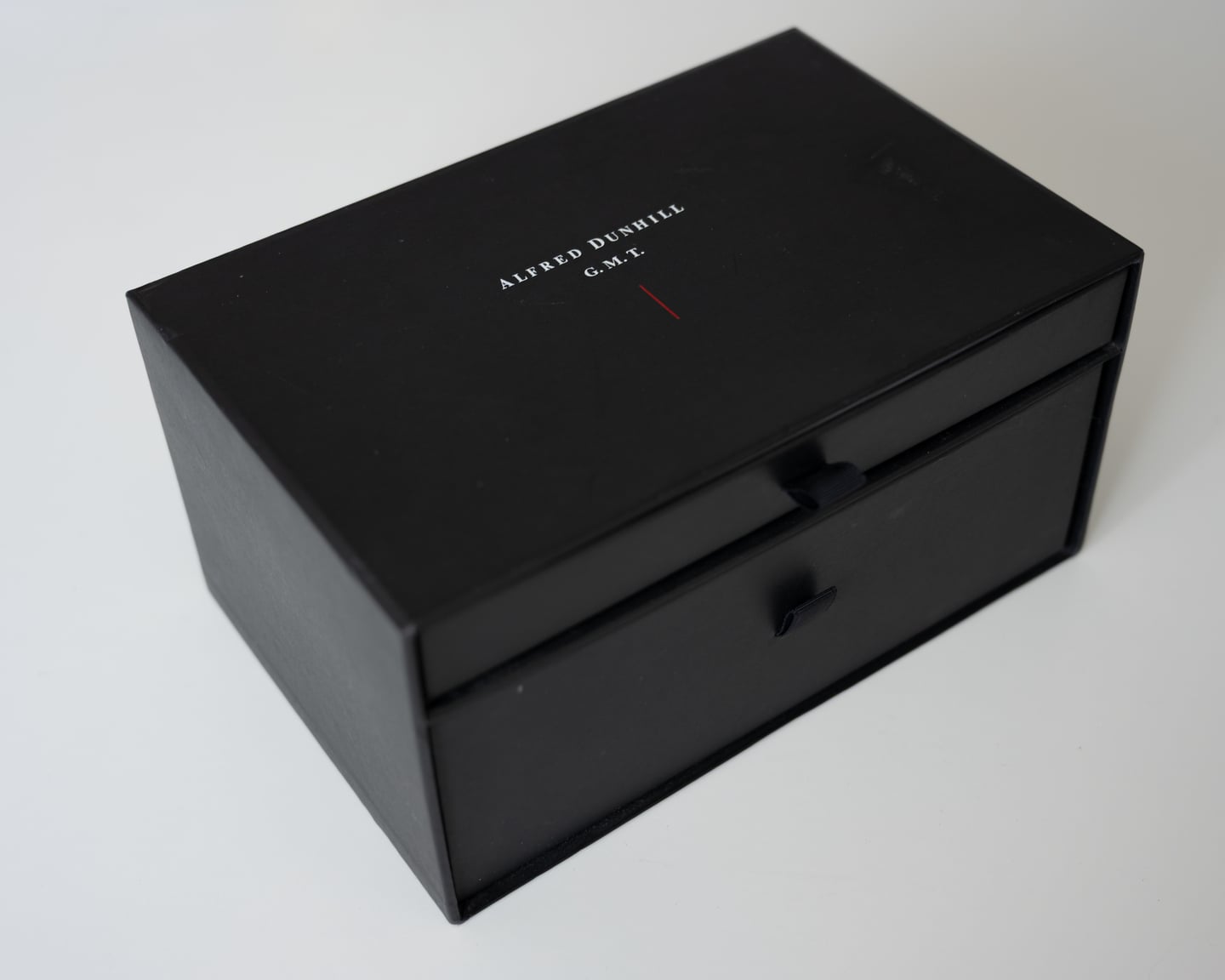 A closed black presentation box photographed against a pale background.