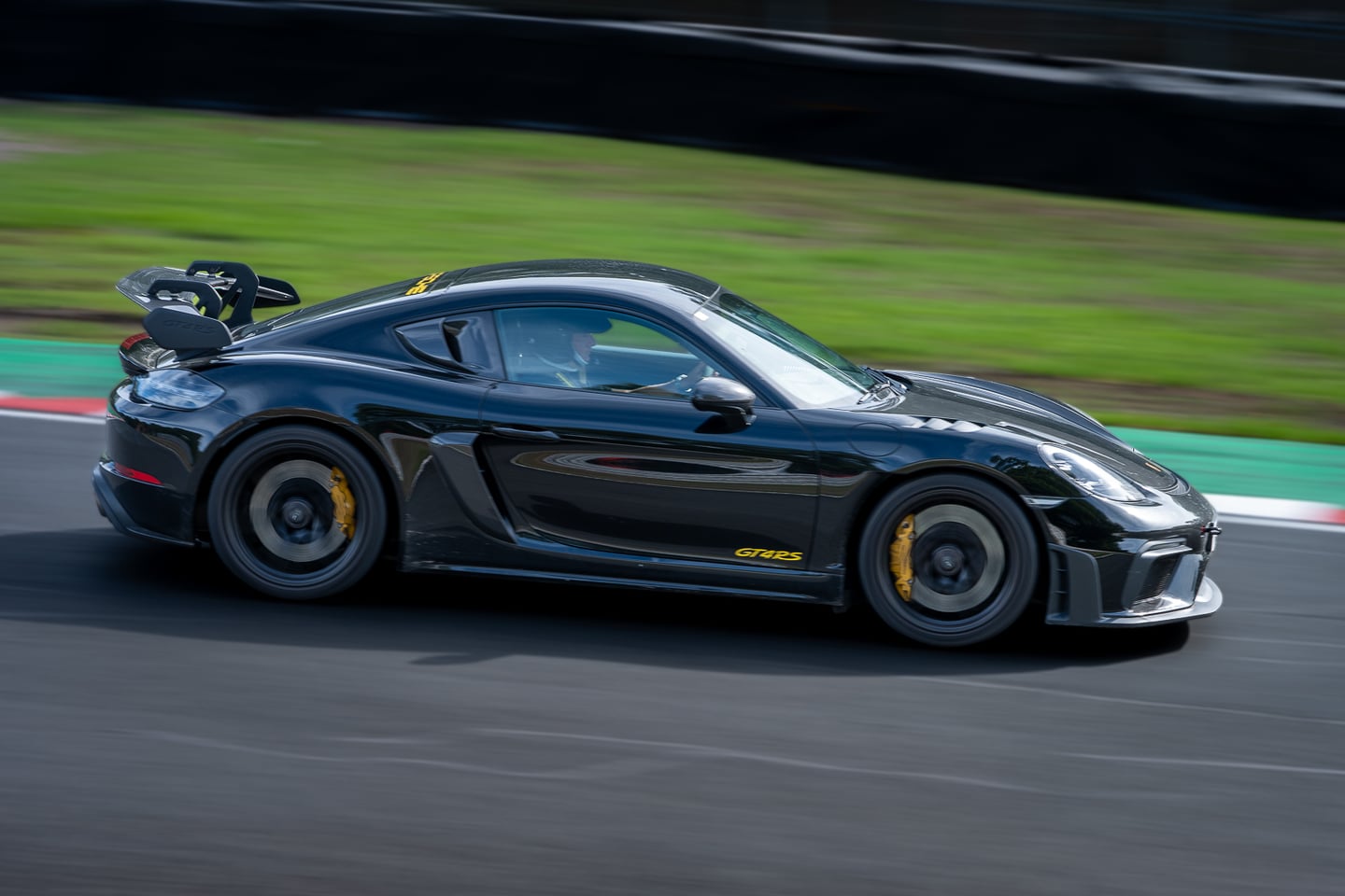 A black sports car speeding around a race circuit.