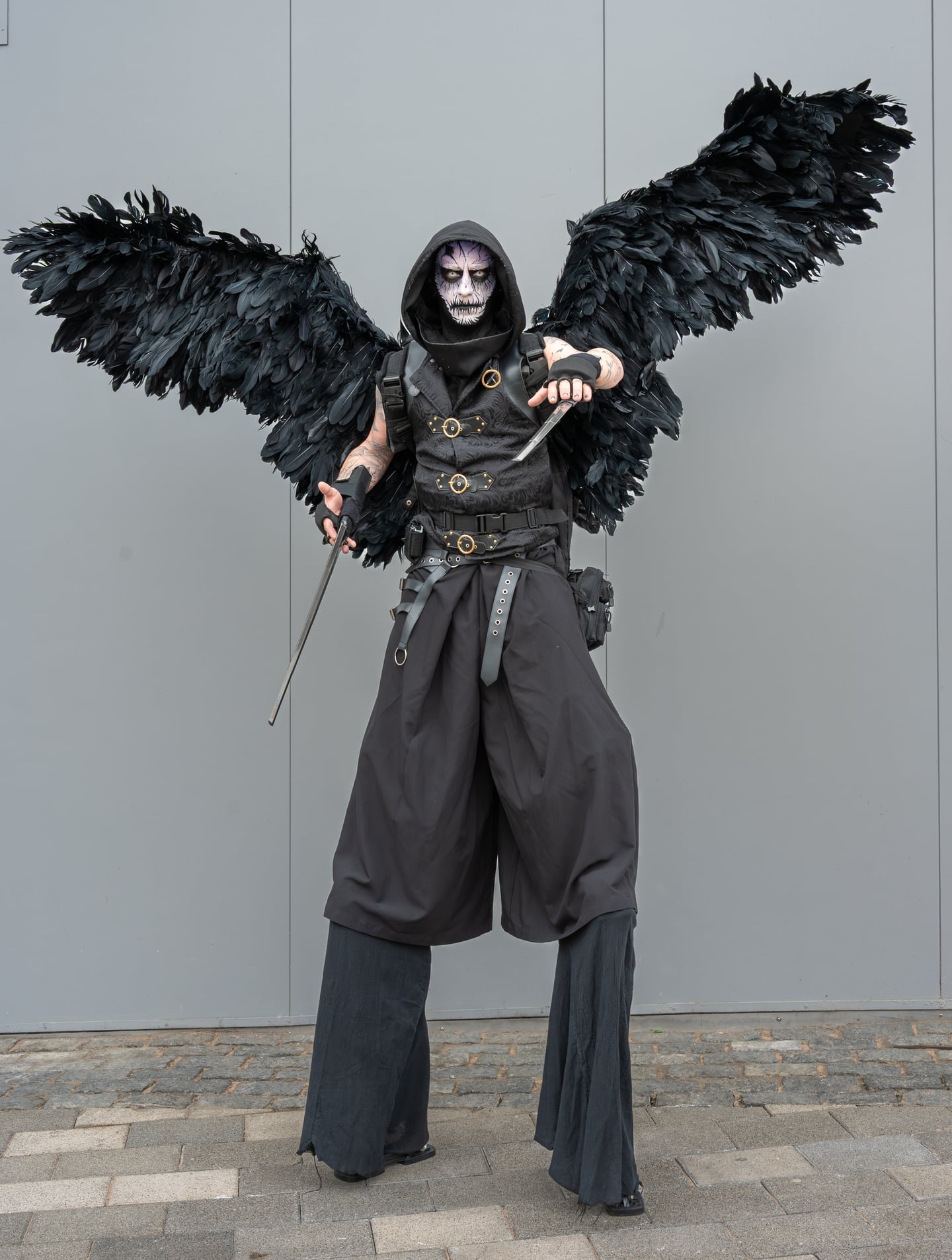 A convention attendee in a dark costume with large black feathered wings.