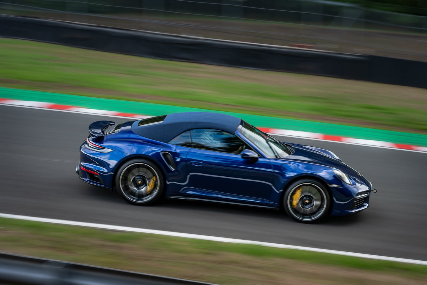 A blue sports car photographed in motion on a race circuit.