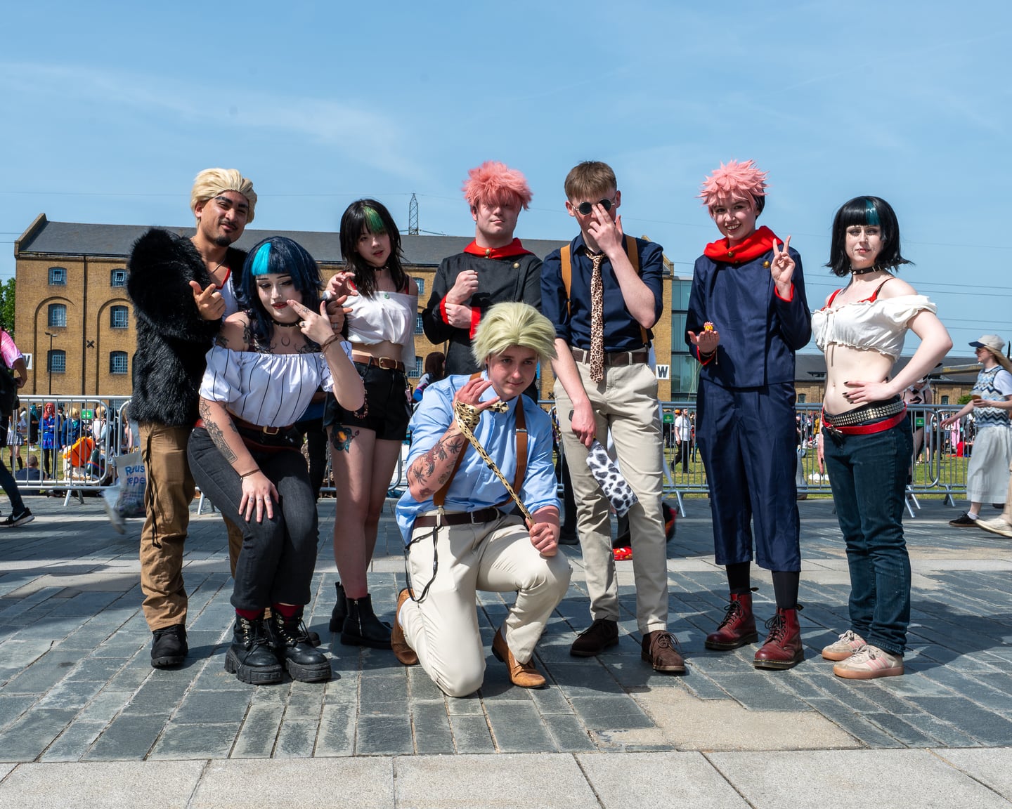 A group of brightly costumed convention attendees posing outdoors.