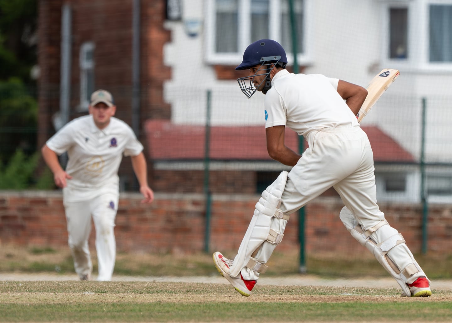 A cricket batter running between the wickets with a bat.