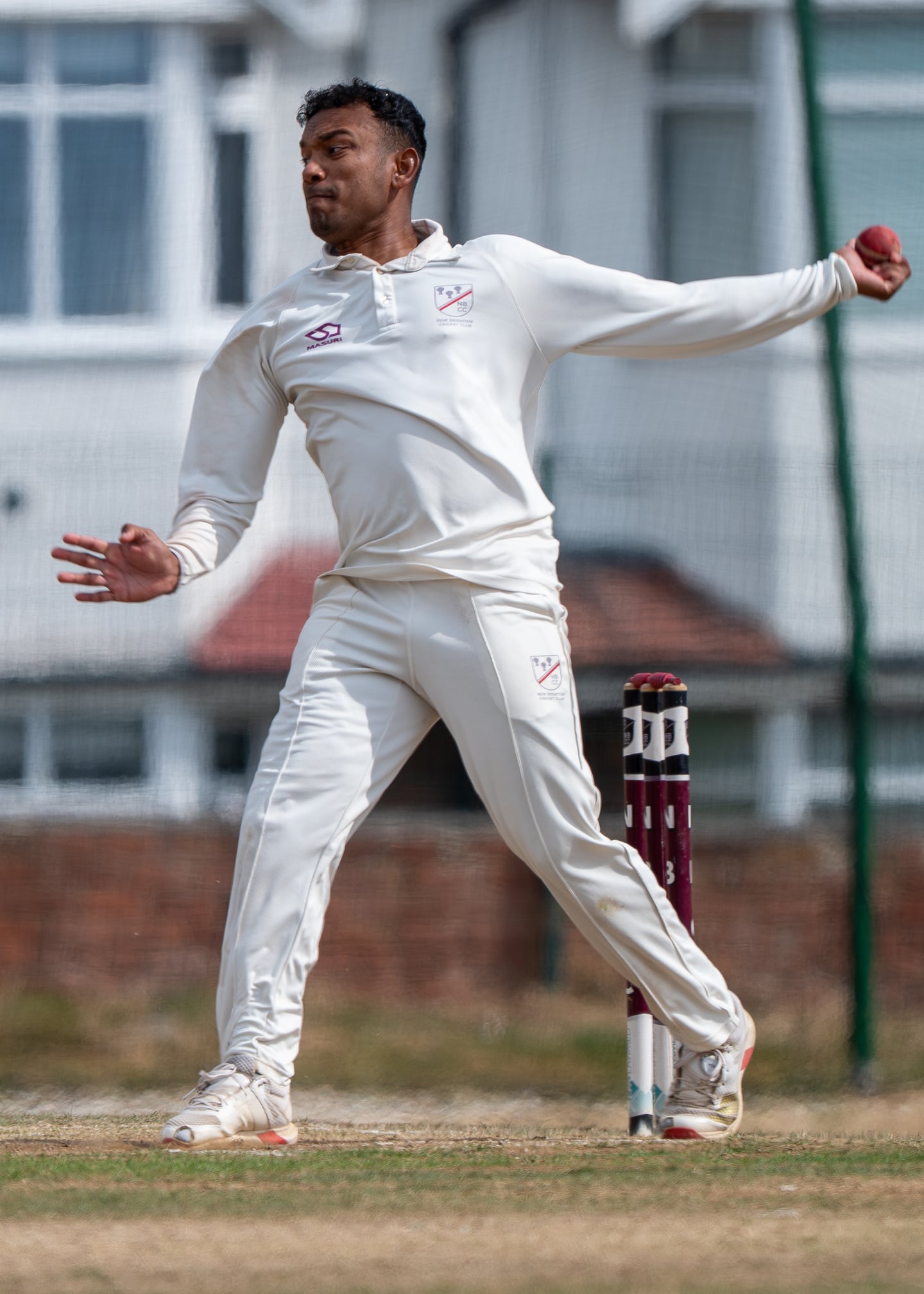 A cricket bowler extending an arm during the bowling action.