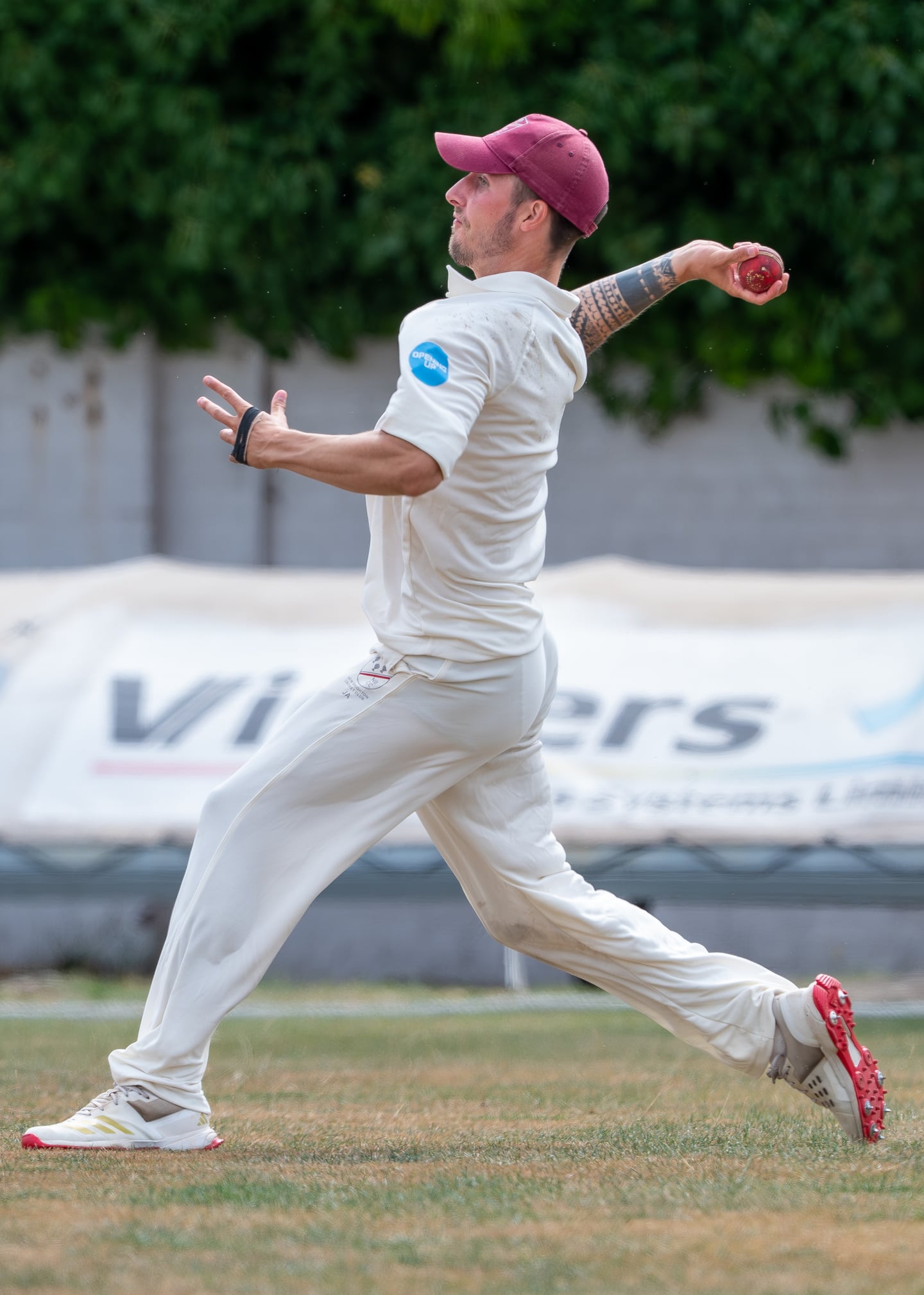 A cricketer in a red cap preparing to bowl.