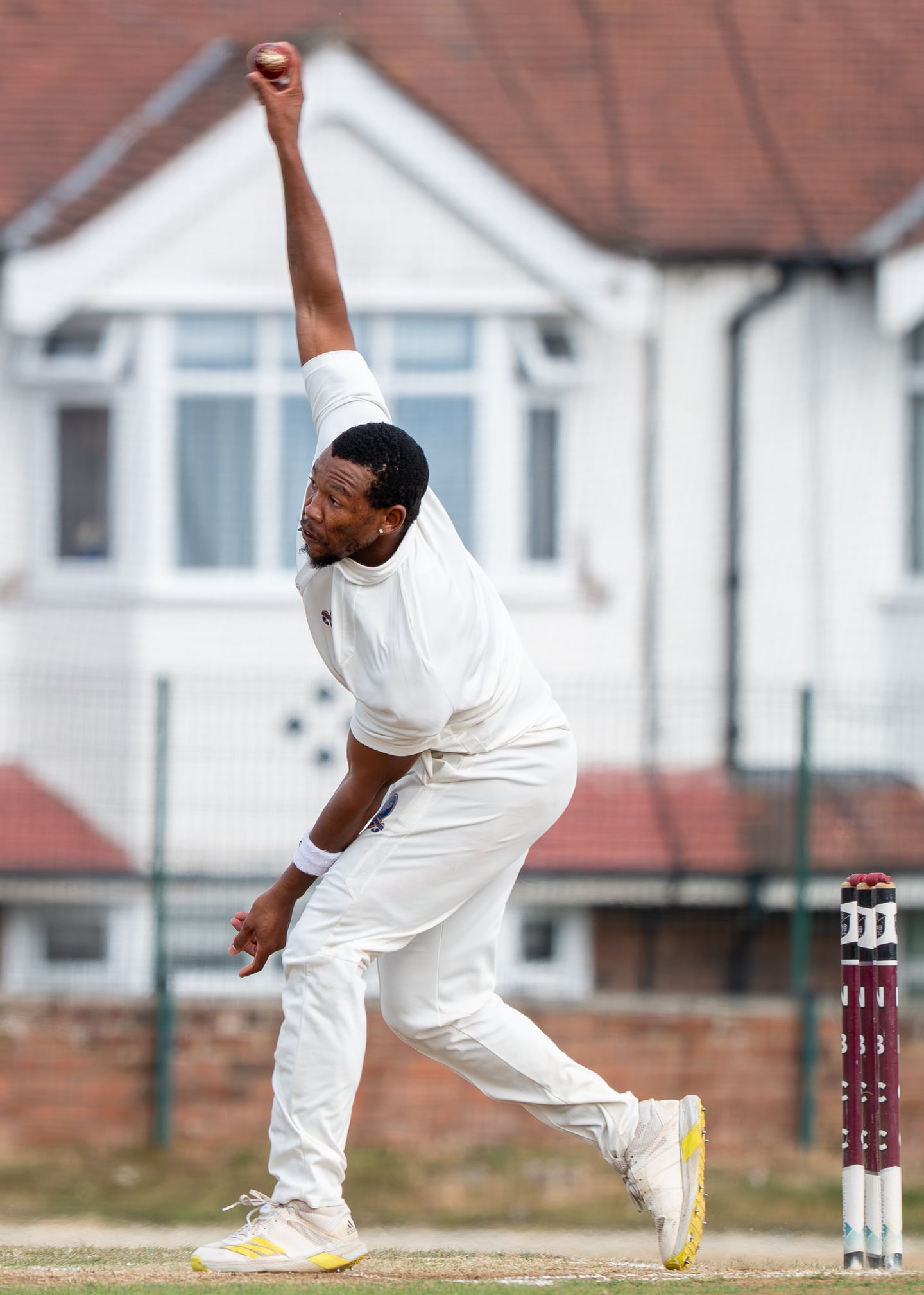 A cricket bowler captured with an arm raised at the point of delivery.