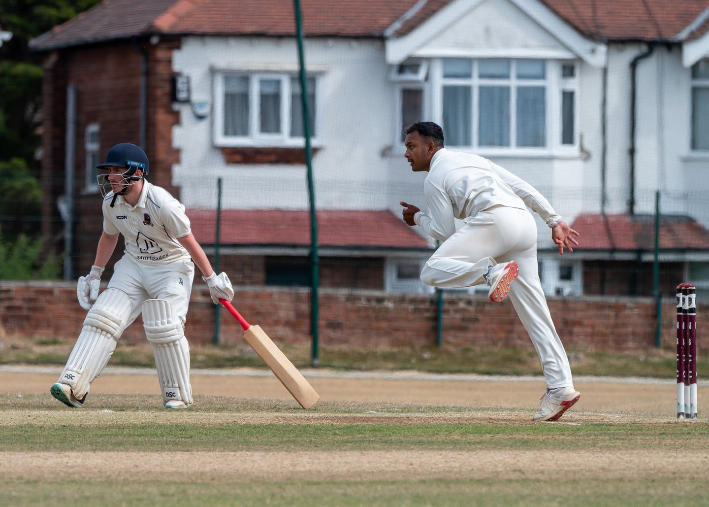 A cricket bowler releasing the ball towards the batter.