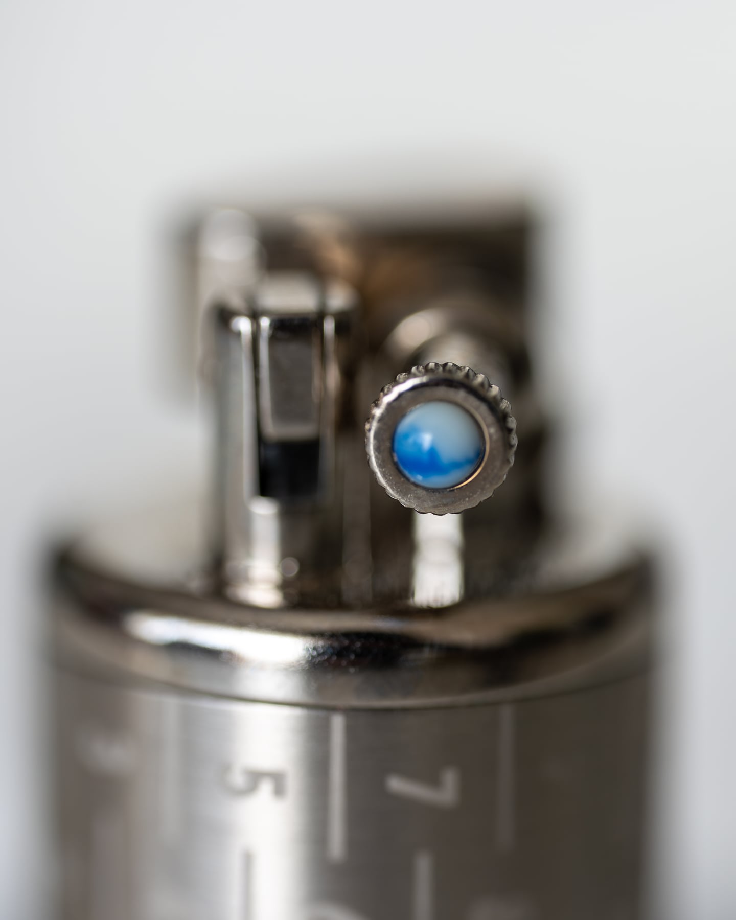 Close-up of a metal lighter with a blue circular detail.