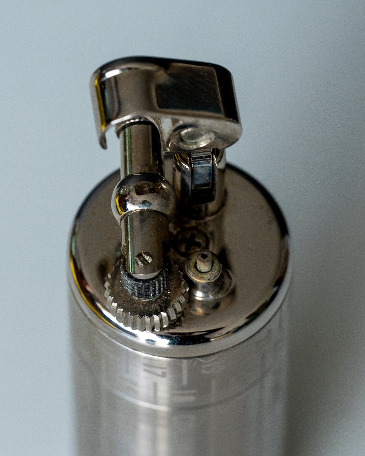 A close view of an open metal lighter and its mechanism.