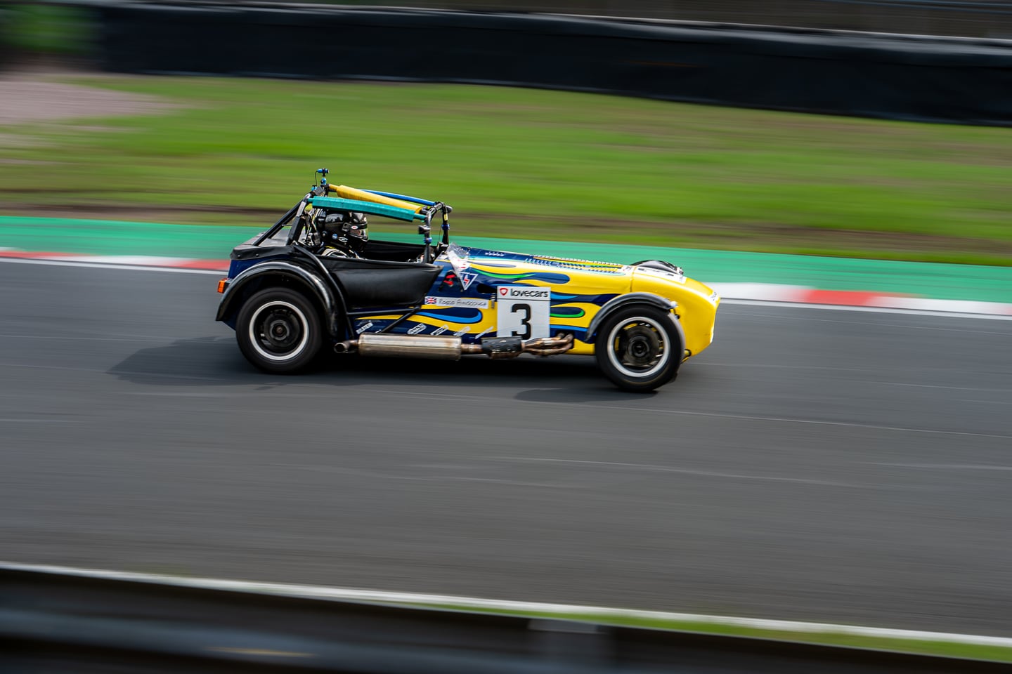 A yellow and green open-top racing car on a circuit.