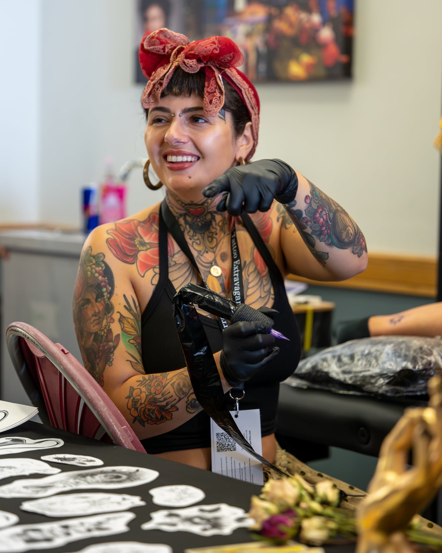 A tattoo artist with a headscarf smiling at the workstation.