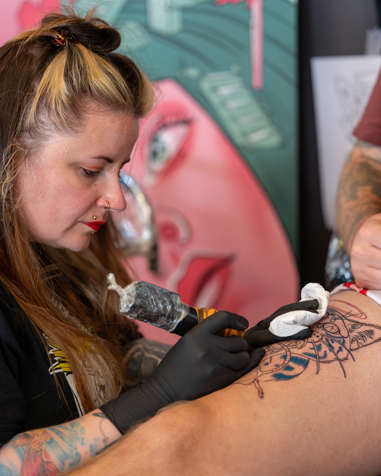 A tattoo artist concentrating on a tattoo near a client's shoulder.