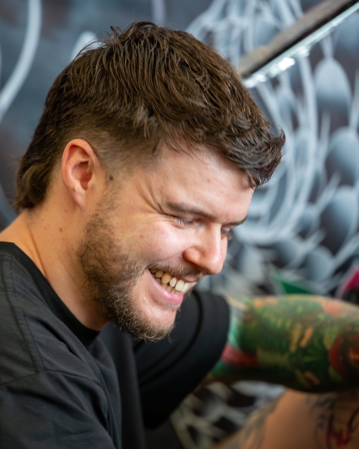 A smiling tattoo artist looking down while working.