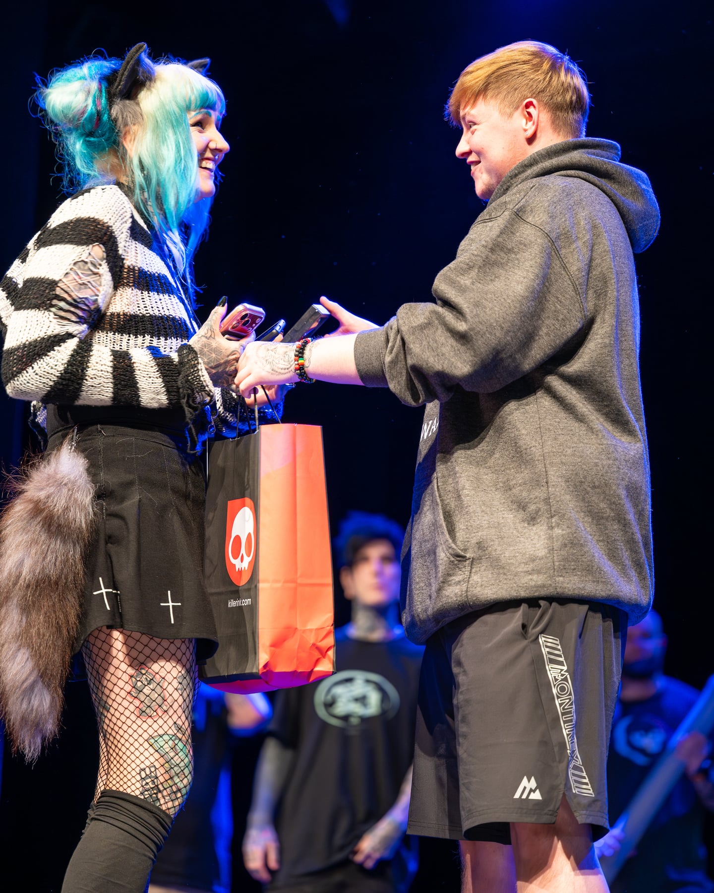 Two people exchanging an award on the tattoo event stage.