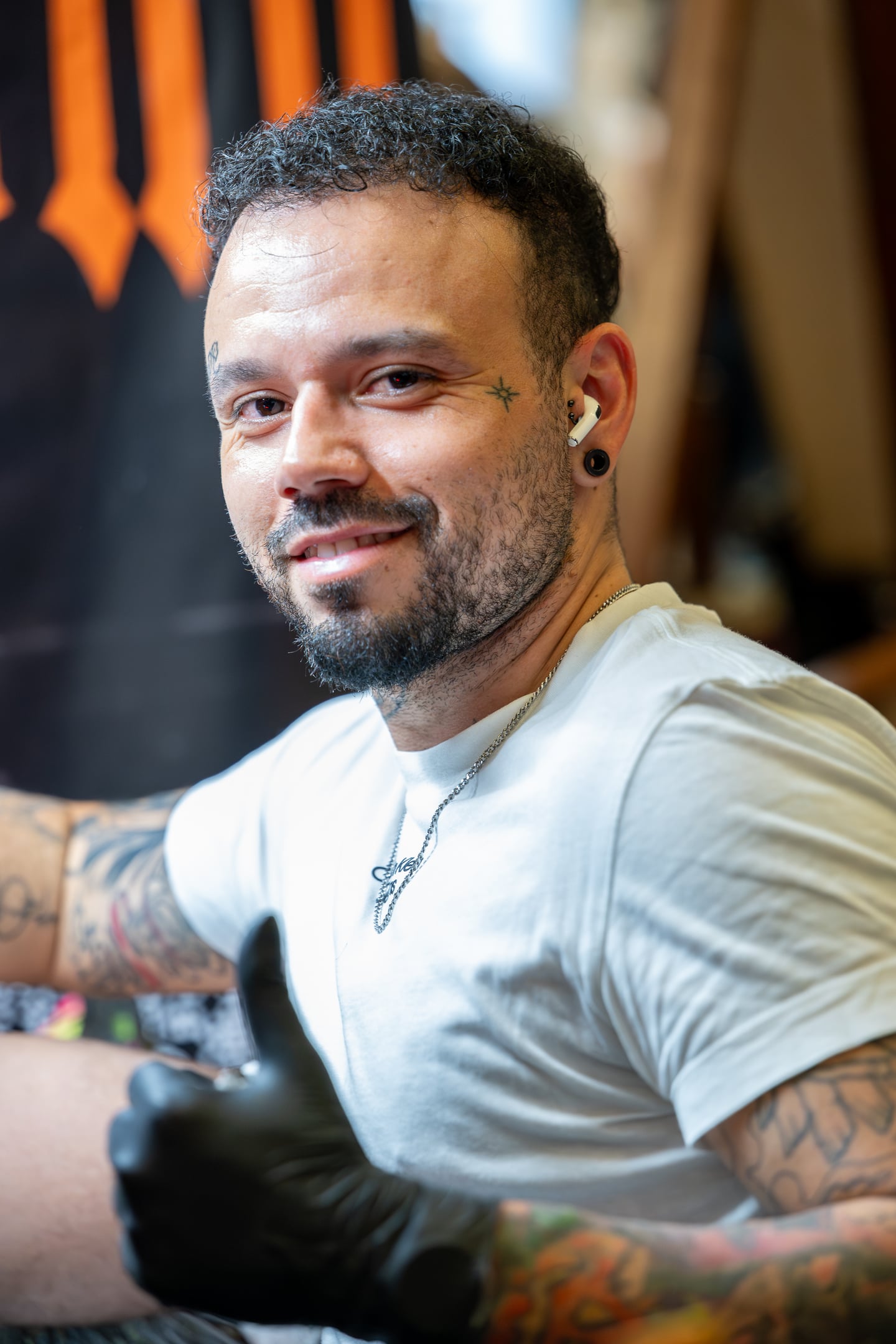 A tattoo artist in a white T-shirt looking towards the camera.