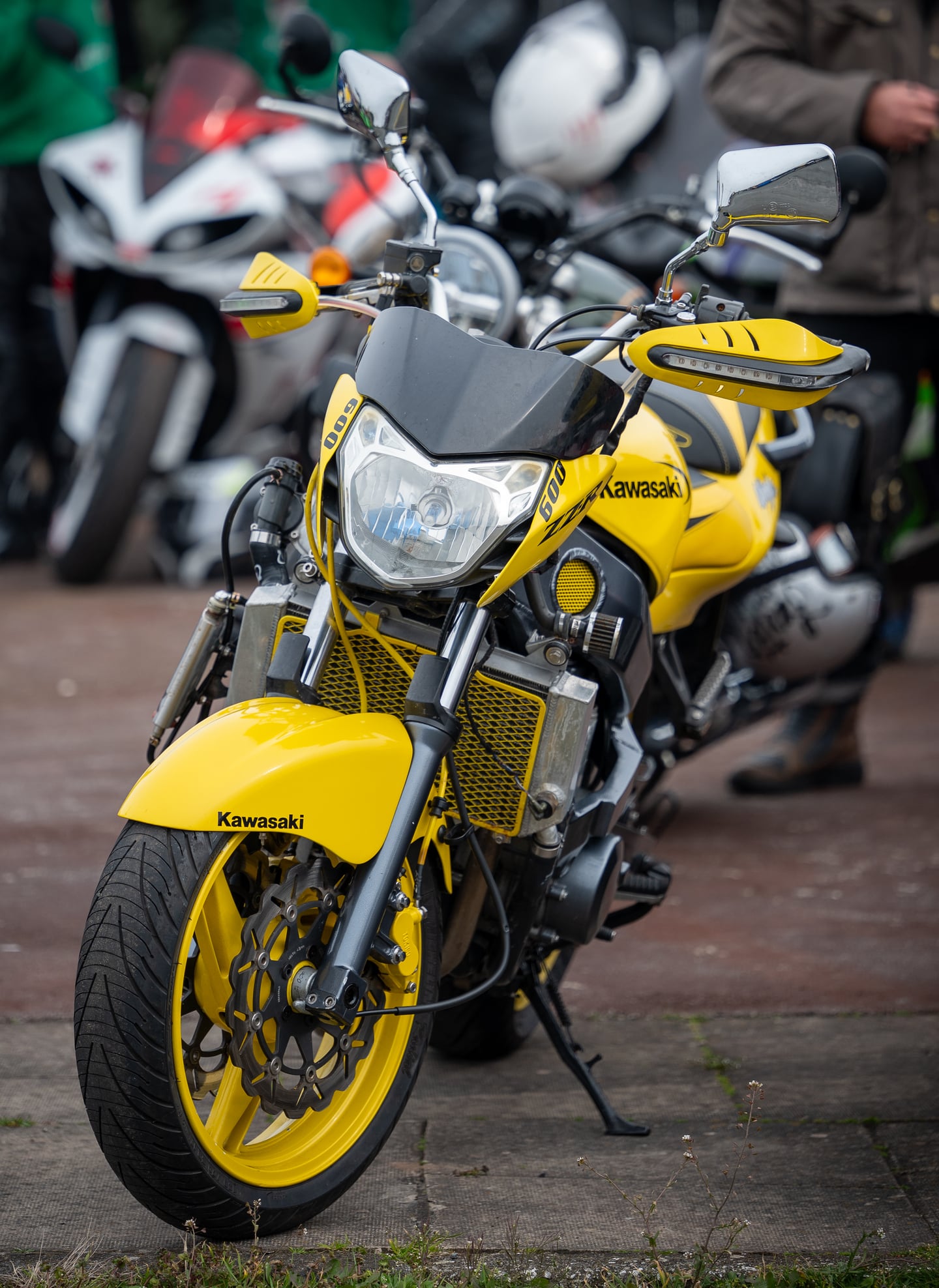 A yellow motorcycle parked beside other motorcycles.